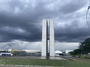 Fotografia do Congresso Nacional sob céu de tempestade, inserida para ilustrar visualmente o clima de tensão e a urgência da pauta ambiental que aguarda os novos parlamentares.